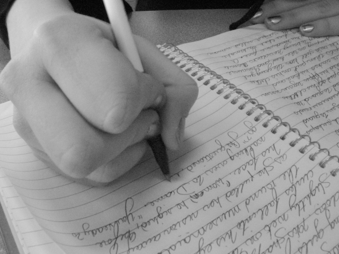 Journal being written in by a hand holding a pen
